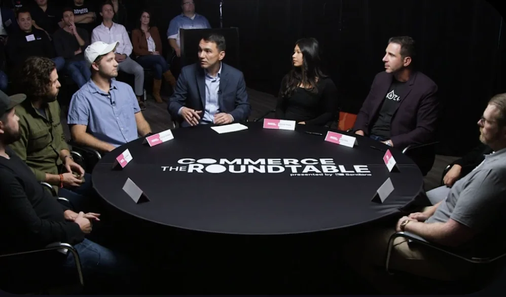 Founders and operators talking around a Commerce Roundtable table presented by Sendlane, with an audience watching
