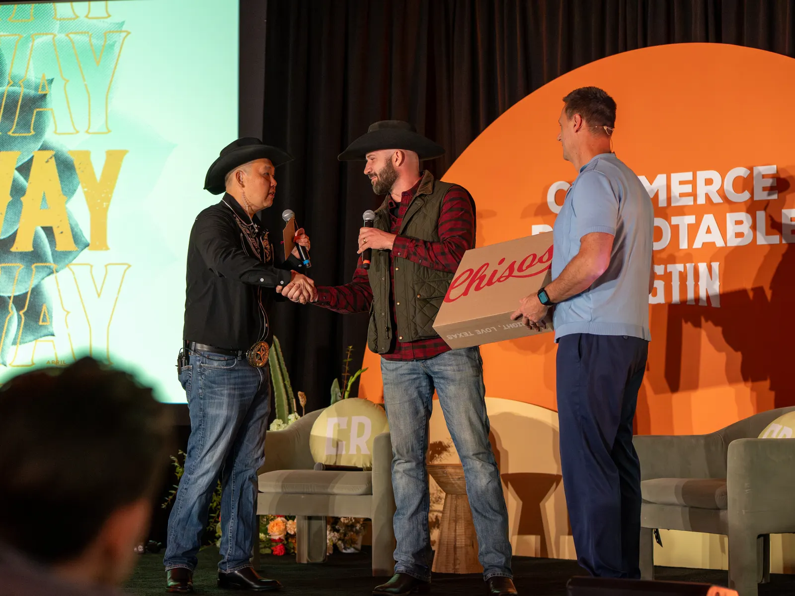 The cowboy hosts handing a prize to a winner