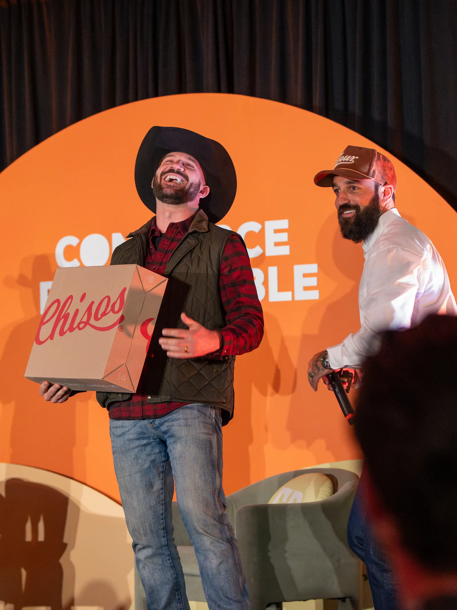 A giveaway winner laughing with a prize on stage