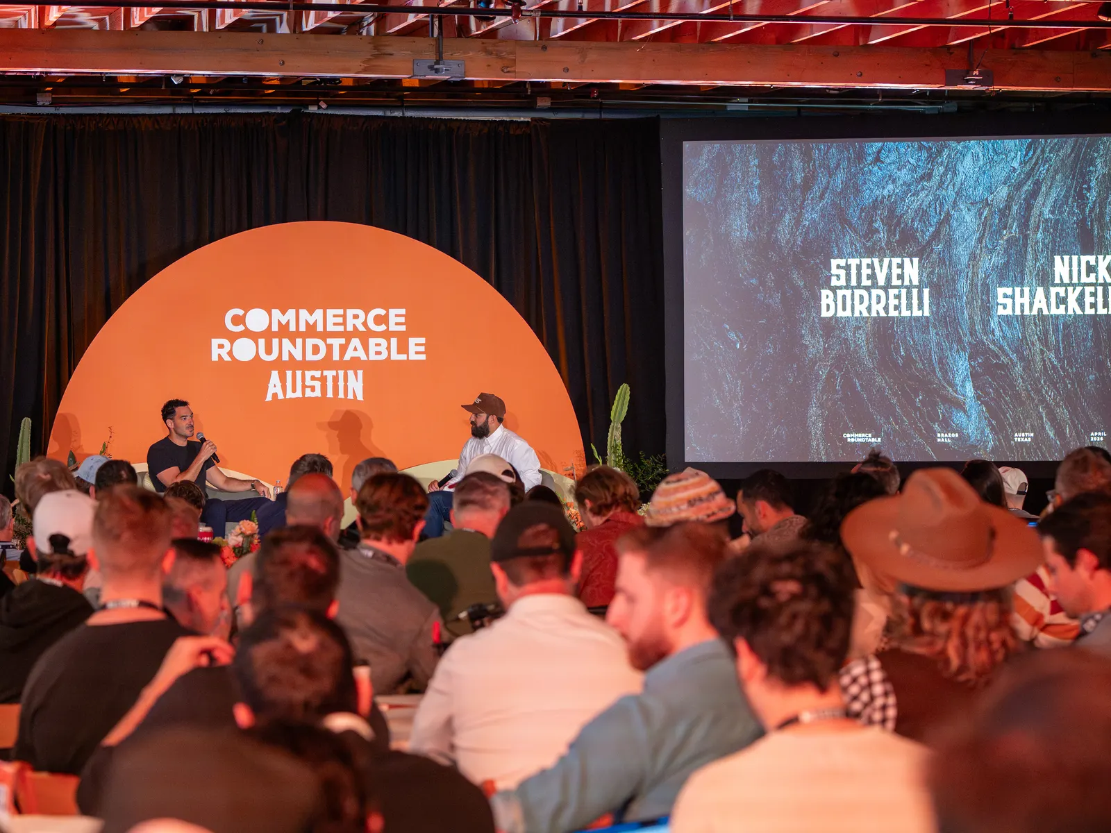 A full audience facing a panel on stage