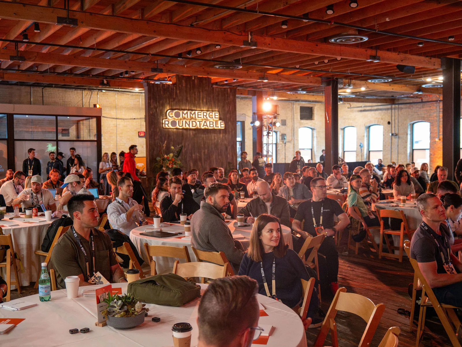 Attendees filling the tables beneath the wooden ceiling at Commerce Roundtable Austin