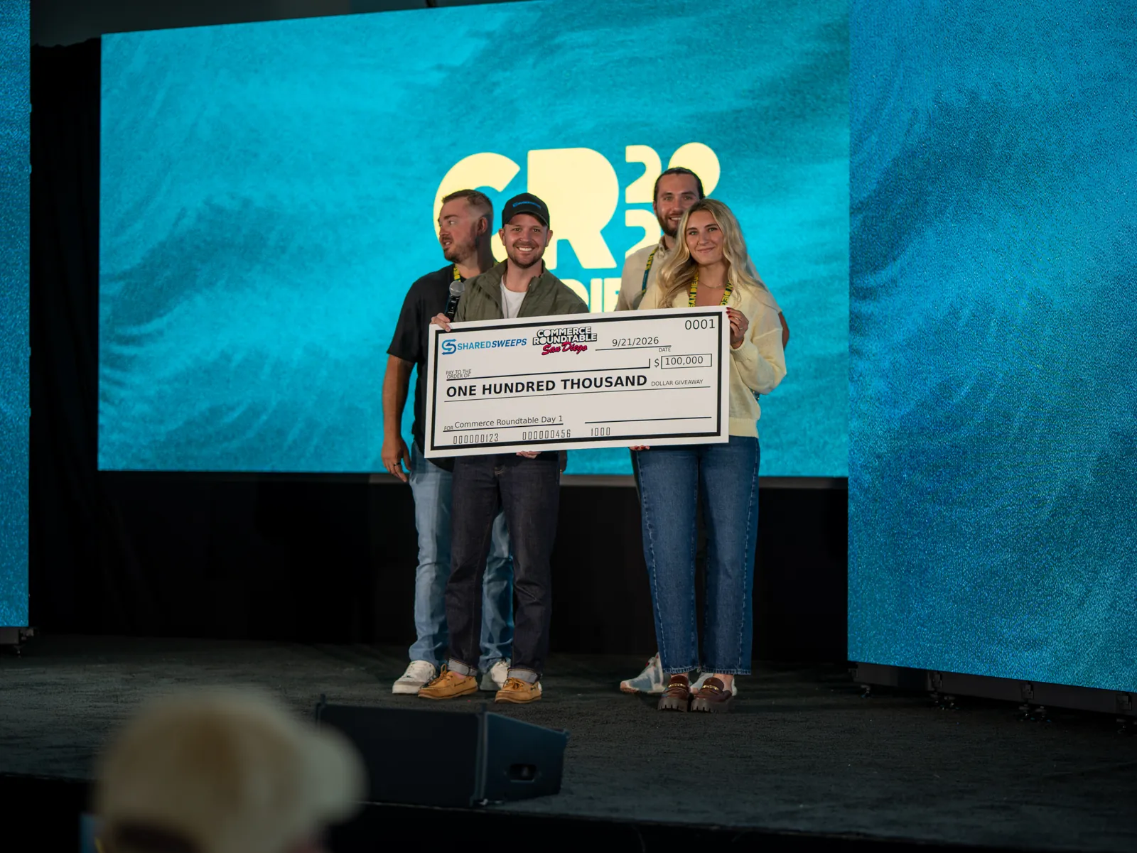 Giveaway winners holding a one hundred thousand dollar check on stage at San Diego 2026