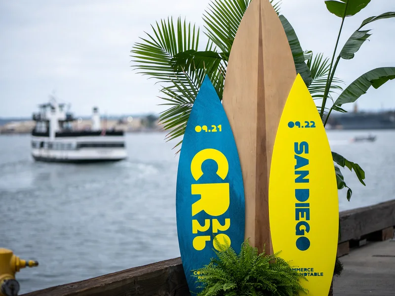 Commerce Roundtable surfboards beside the harbor with a boat passing behind them