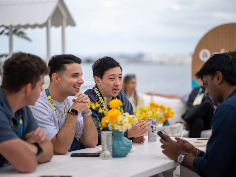Attendees smiling and sharing a conversation around a waterfront table