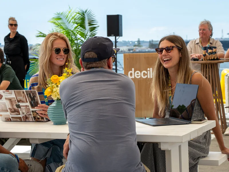 Attendees laughing together over a conversation beneath the waterfront canopies